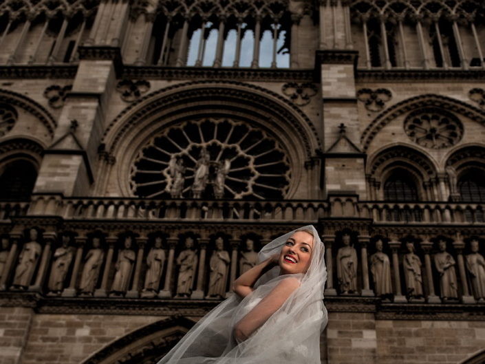 Mireasa în fața catedralei Notre-Dame din Paris, cu voalul în vânt