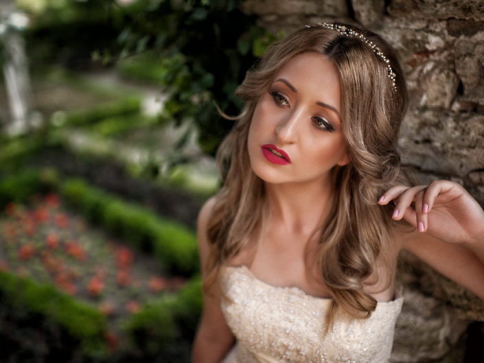 Mireasă blondă în grădină, portret cu flori roșii în fundal