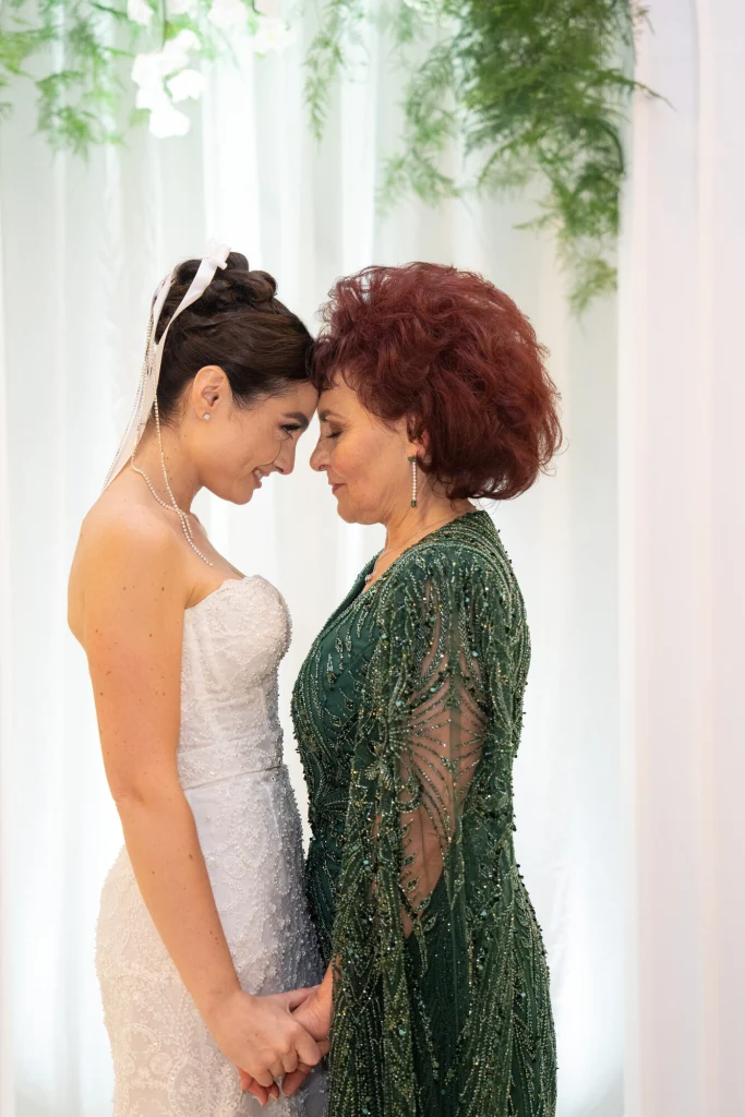 Mireasa și mama ei îmbrățișate în fața arcadei cu flori la nunta de la Diplomatic Mamaia
