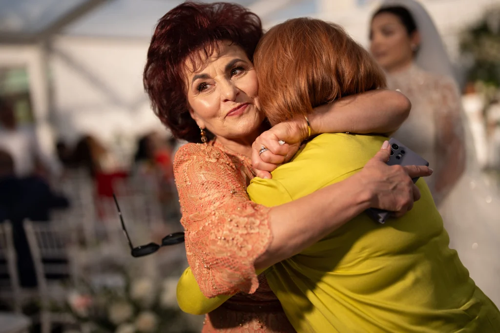 Două invitate se îmbrățișează emoționate la ceremonia de nuntă