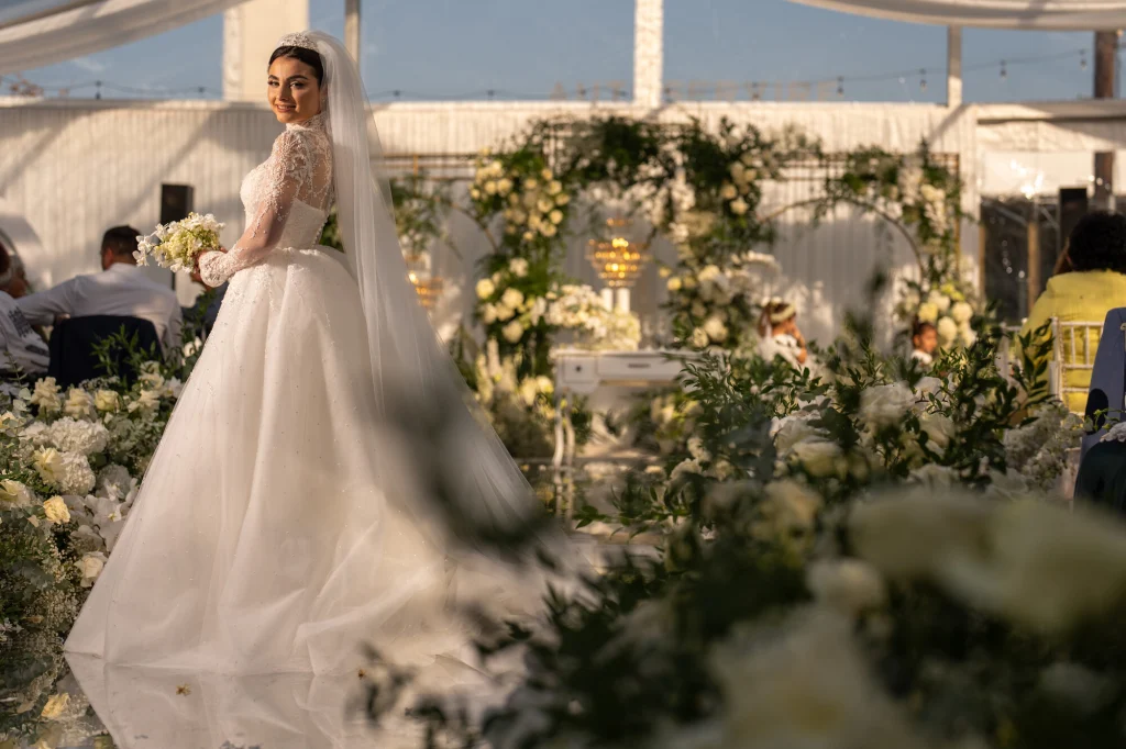 Mireasa pășind pe culoarul dintre flori albe spre ceremonia din cortul Diplomatic Mamaia