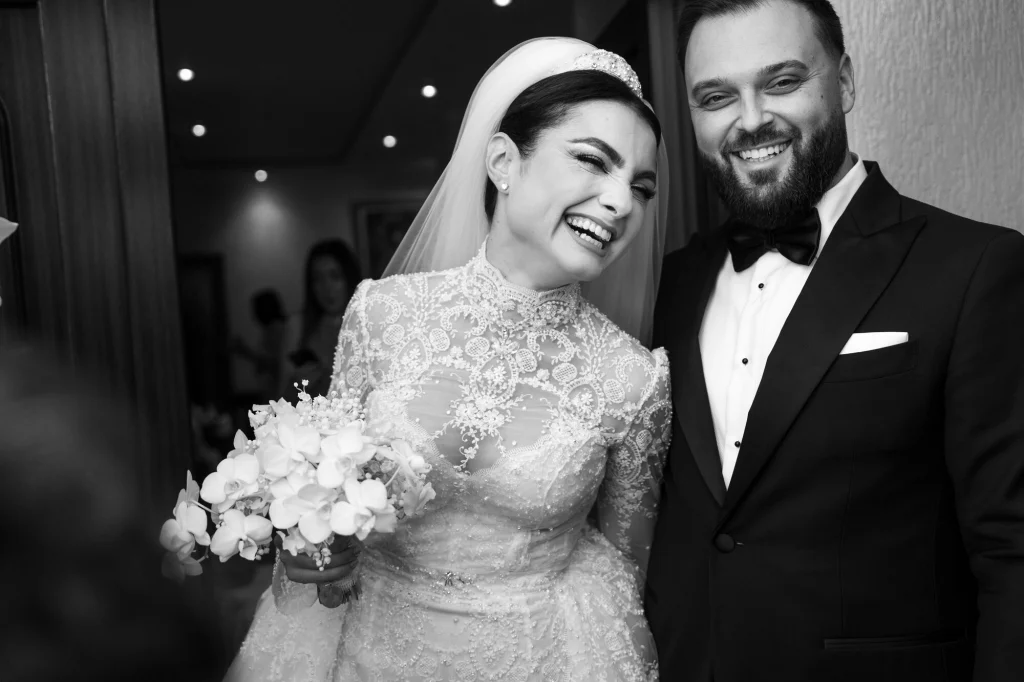 Fotografie alb-negru cu mireasa și mirele râzând unul lângă altul