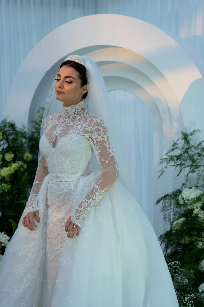 Mireasa în rochie de dantelă cu guler înalt, sub arcada albă cu verdeață de la Diplomatic Mamaia