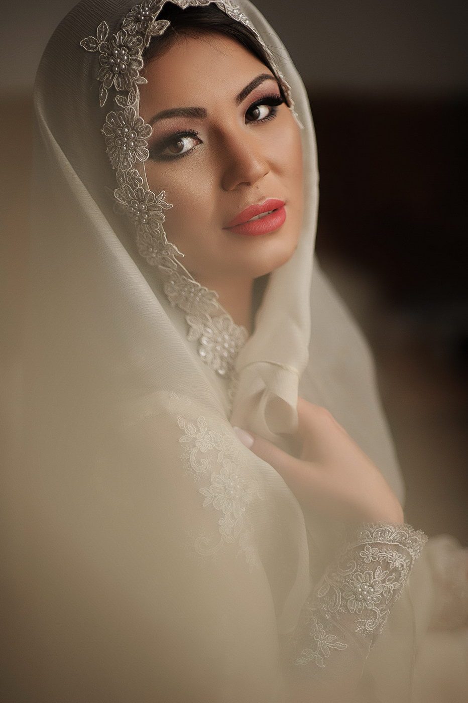 Portret de mireasă cu voalul de dantelă așezat pe cap, privind spre aparat, în lumină moale