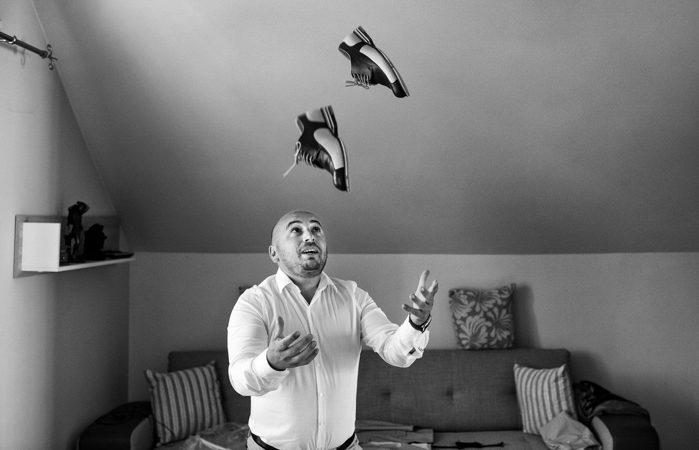 Mirele în cămașă aruncă pantofii în aer în cameră, fotografie alb-negru